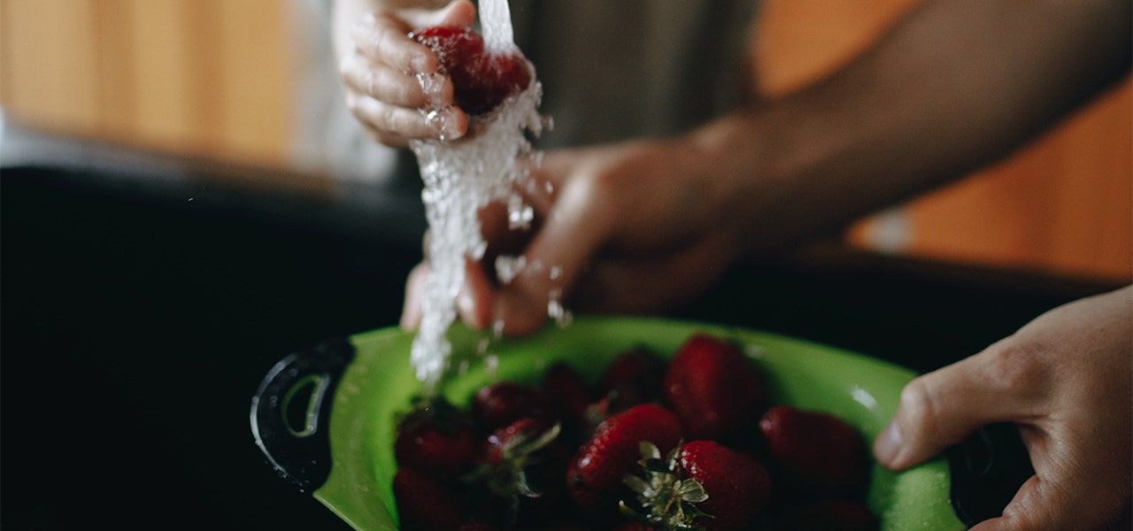 Someone rinsing strawberries after removing them from plastic packaging