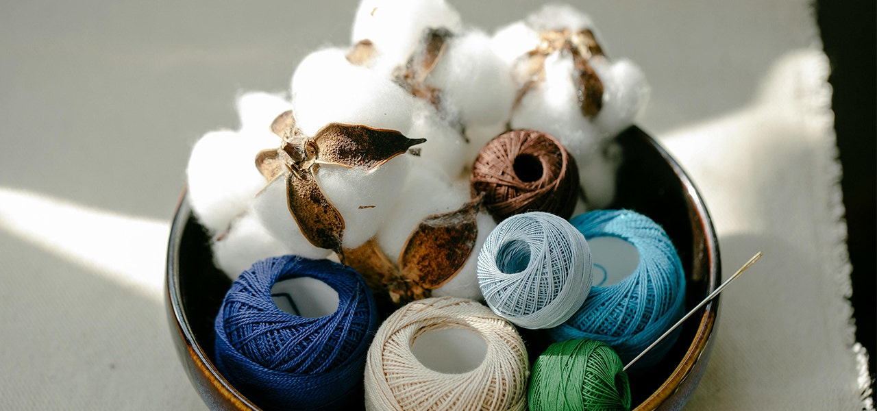 Wooden bowl containing organic cotton blossoms and yarn