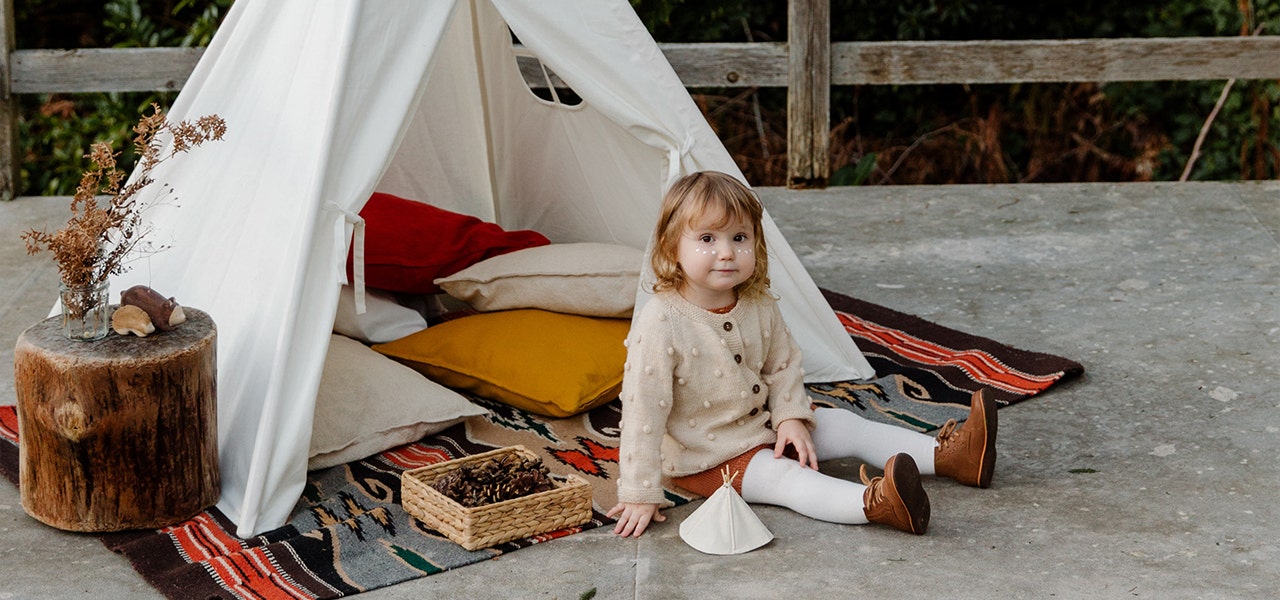 Toddler sitting by an outdoor play tent in the winter time to get fresh air