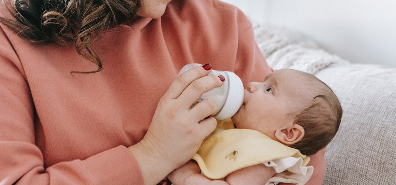 Mother feeding a baby from a plastic bottle that likely contains phthlalates