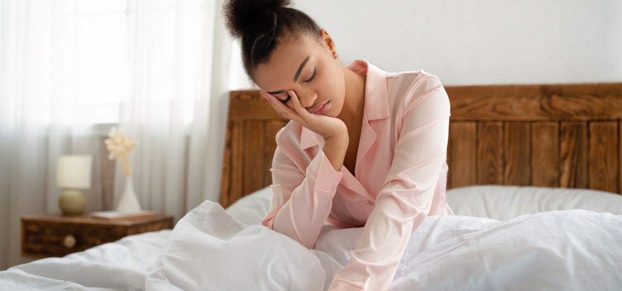 Tired woman sitting up in bed, half asleep
