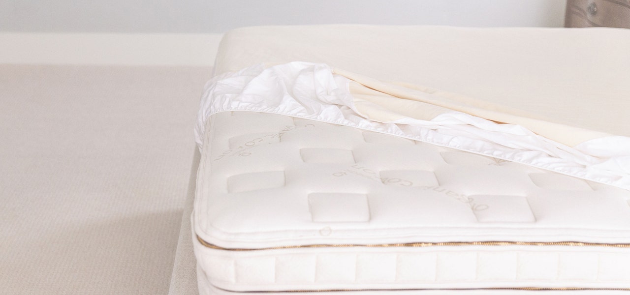 Naturepedic organic mattress with an organic mattress pad pulled partly off