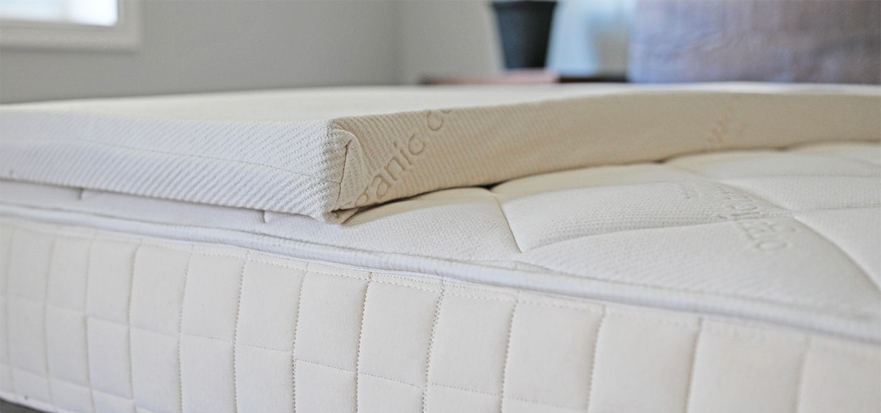 Organic latex mattress topper partially placed on mattress