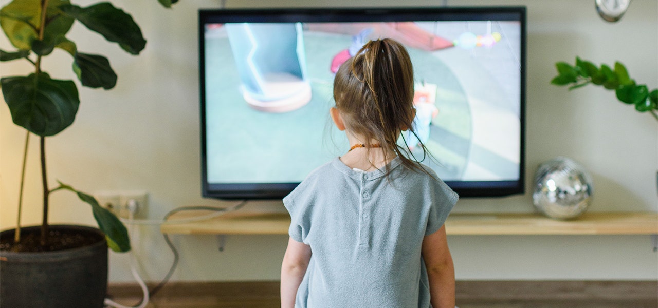 Young girl watching cartoons on television, absorbing blue light