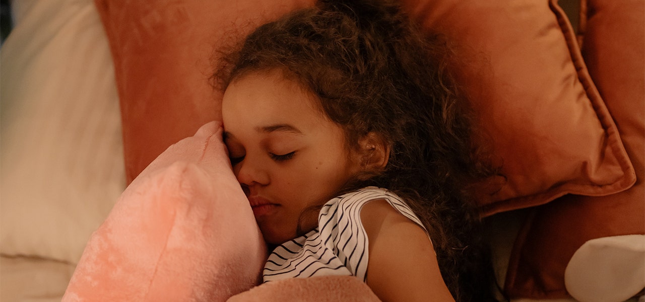 Little girl sleeping on a few throw pillows