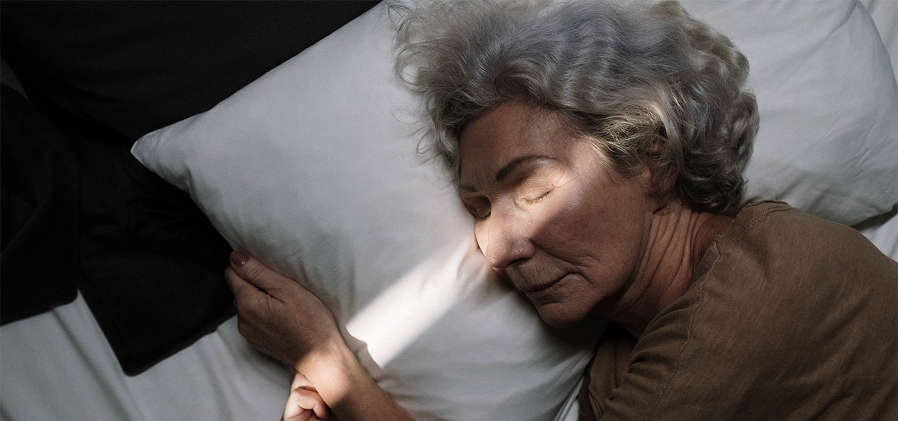 Elderly woman sleeping witn sunsight streaming in through the window