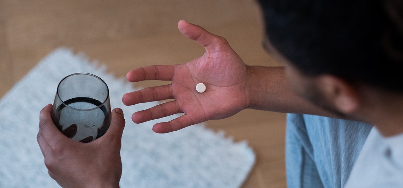 Man taking prescription medication with a glass of water