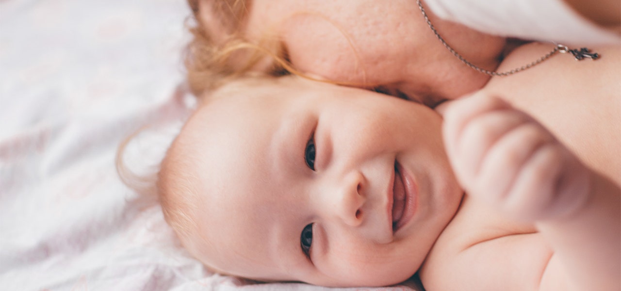 Mother and smiling toddler snuggling in bed