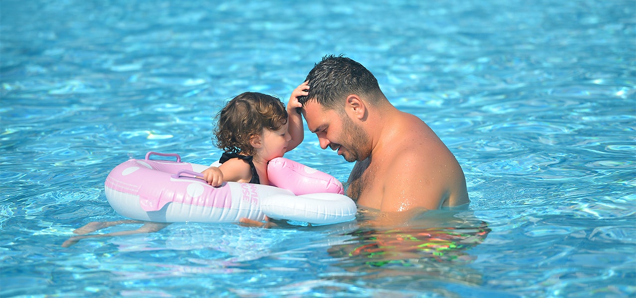 Father and daughter swimming together in a swimming pool