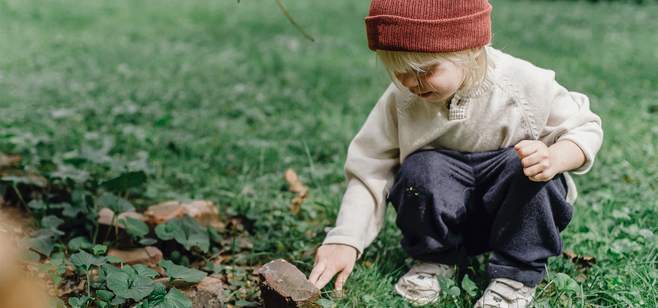 Small child exploring the grass and rocks outside