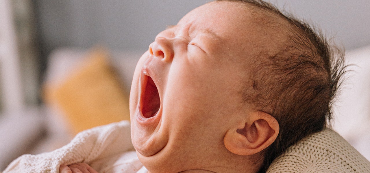 Newborn baby wrapped in a blanket and yawning
