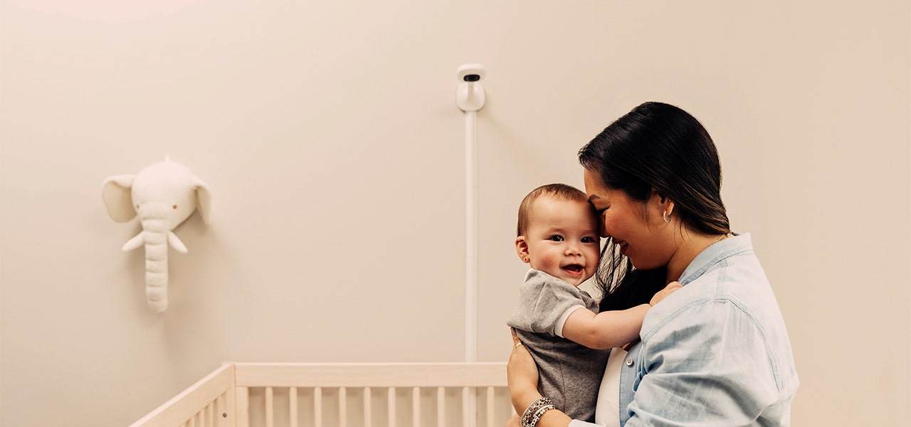 mom holding baby in nursery with baby monitor