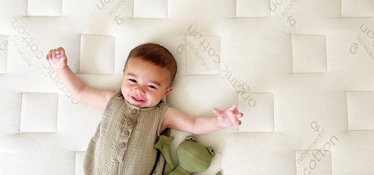 Smiling baby lying on an EWG VERIFIED mattresss