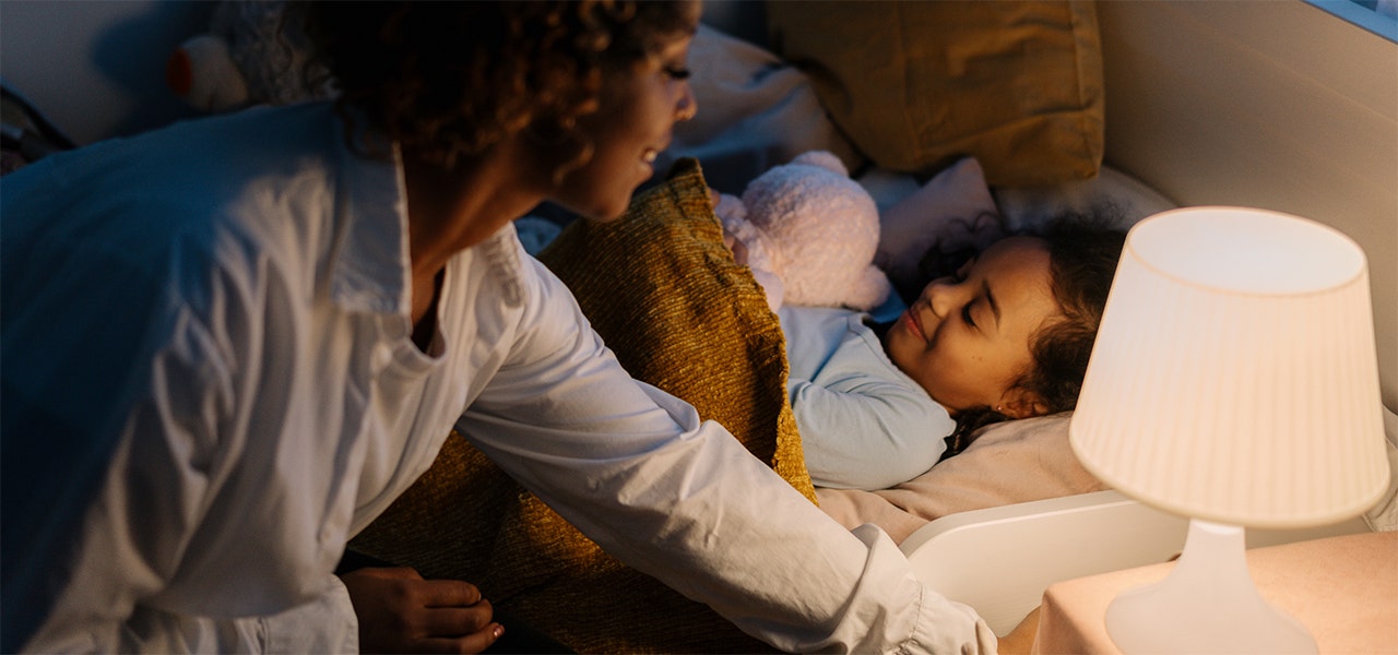 parent tucking child into bed