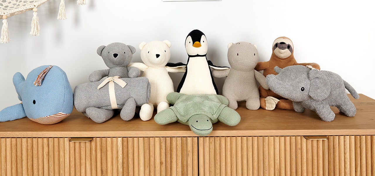 lineup of naturepedic organic stuffed animals, including a bear, a sloth, a polar bear, a penguin, and a hippo, a turtle, an elephant, and a whale