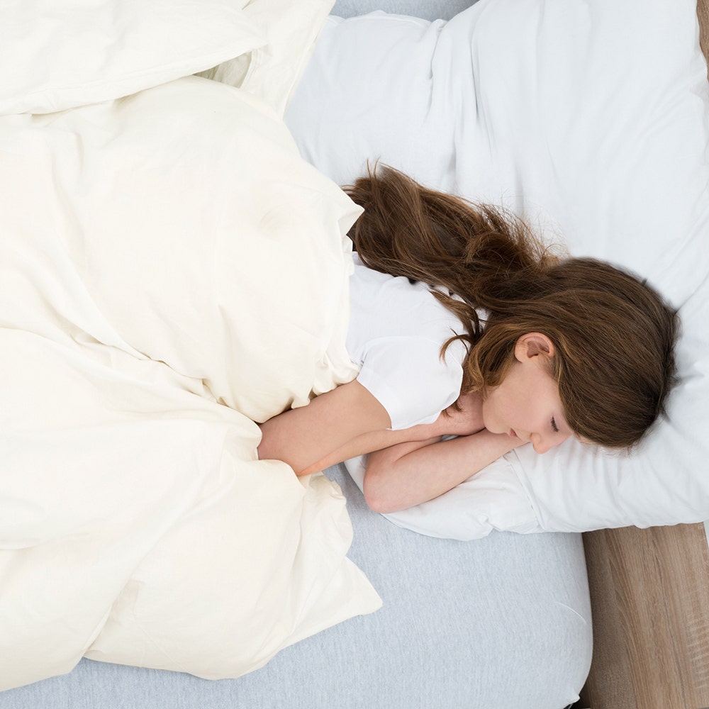 Girl laying in bed under alpaca duvet insert